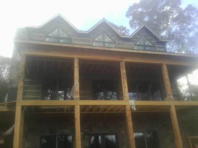 Dormers and porch framing on a large log home under construction — Roof Coating work by our crew in South Plymouth