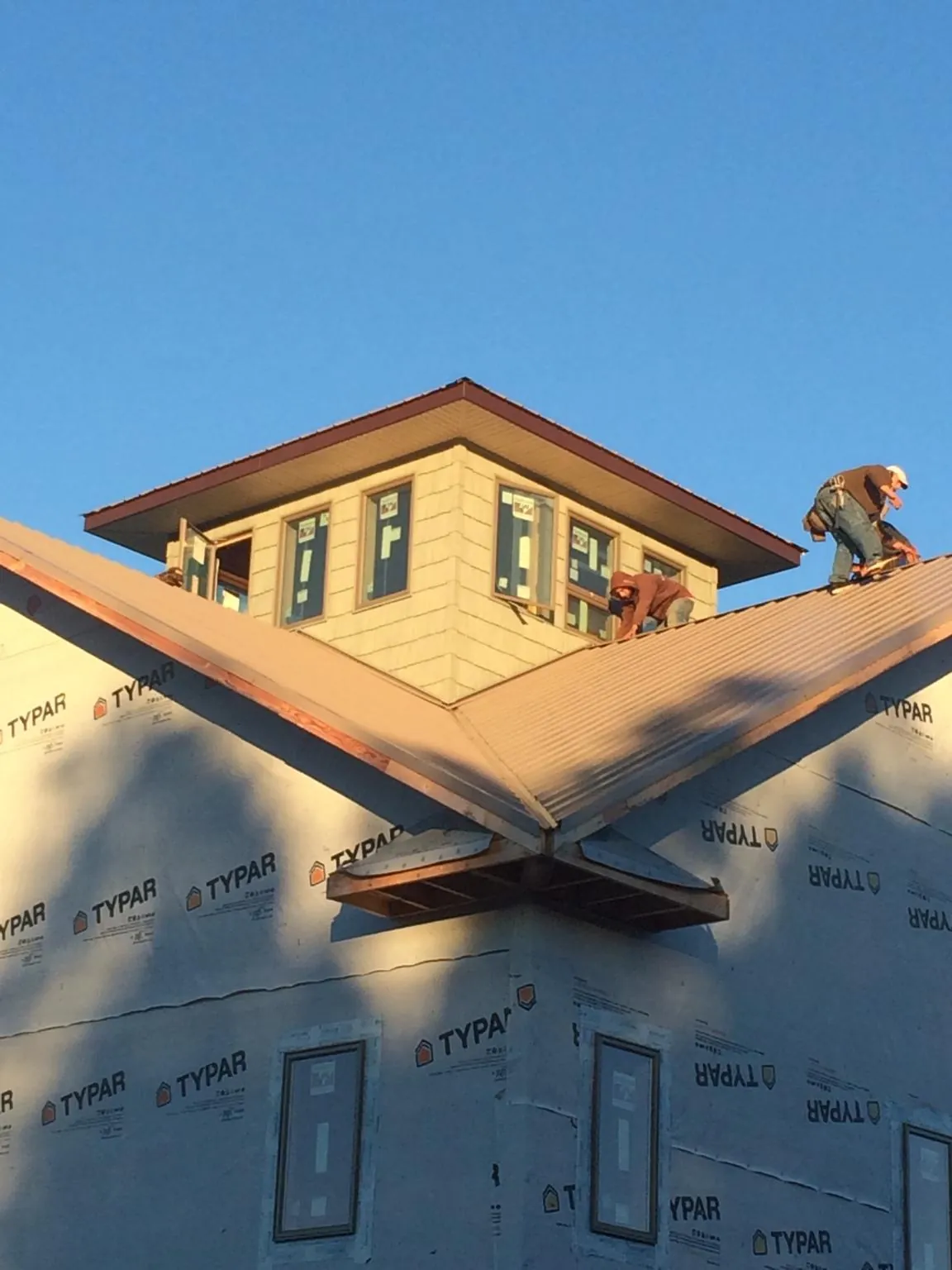 Roofers working around a rooftop cupola on a new metal roof at sunset — Roof Waterproofing in South Plymouth by Roofing Brothers